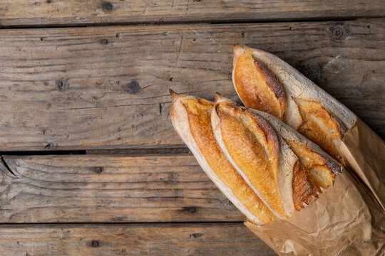 Close-up of baguettes in paper bag on wooden table