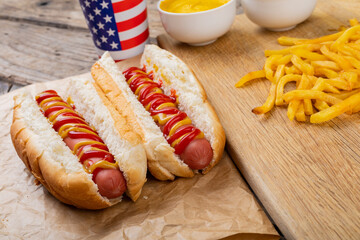 Hot dogs with tomato and mustered sauce served with french fries and drink served at table