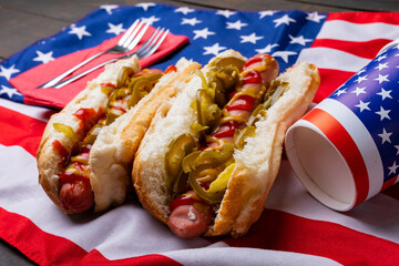 Close-up of hot dogs with jalapeno served on american flag with fork and disposable cups