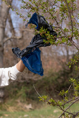 Man hand picking up rubbish plastic bag from a tree helping enviroment