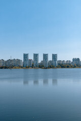 Fototapeta na wymiar A city on the shore of a wide lake. A river and tall buildings on the far bank