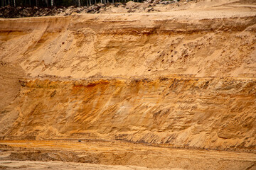 Textural sand, with  relief surface, multi-colored layers and different in size of granules, in outdoor sand career, after mining ore and sand for construction.