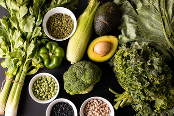 Overhead view of various green vegetables, fruit, herb with seeds and legumes on table