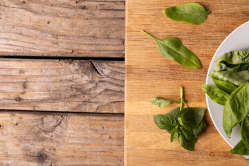 Fototapeta na wymiar Overhead view of fresh baby spinach on wooden cutting board at table