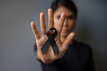 Woman holding black Ribbon for Melanoma and skin cancer, Vaccine injury awareness month, grief and rest in peace. Healthcare and Racist concept