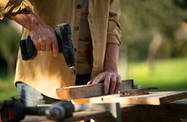 Close-up of handyman carpenter working in carpentry diy workshop outdoors with drill.