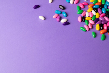 High angle view of copy space by multi colored candies on purple background