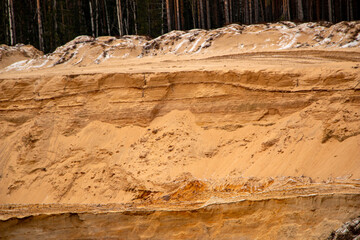 Textural sand, with  relief surface, multi-colored layers and different in size of granules, in outdoor sand career, after mining ore and sand for construction.