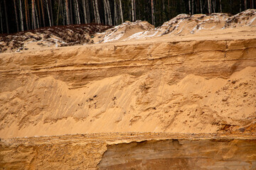 Textural sand, with  relief surface, multi-colored layers and different in size of granules, in outdoor sand career, after mining ore and sand for construction.