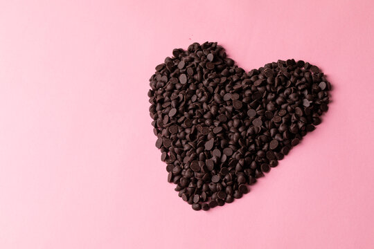 High angle view of fresh chocolate chips arranged heart shape by copy space against pink background - Powered by Adobe