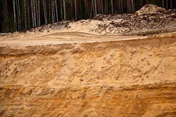Textural sand, with  relief surface, multi-colored layers and different in size of granules, in outdoor sand career, after mining ore and sand for construction.