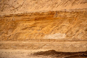 Textural sand, with  relief surface, multi-colored layers and different in size of granules, in outdoor sand career, after mining ore and sand for construction.