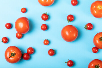 Overhead view of fresh tomatoes scattered over blue background