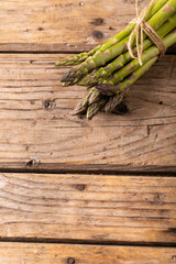 Overhead view of string tied raw green asparagus bunches on wooden brown table