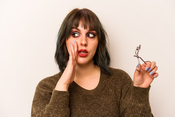 Young caucasian makeup artist woman holding a eyelash curler isolated on white background is saying...
