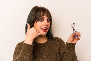 Young caucasian makeup artist woman holding a eyelash curler isolated on white background showing a...