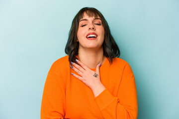 Young caucasian woman isolated on blue background laughs out loudly keeping hand on chest.