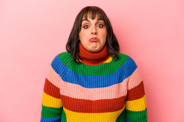 Young caucasian woman isolated on pink background shrugs shoulders and open eyes confused.