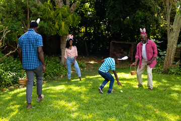 Fototapeta premium Plauful african american multigenerational family in bunny ears with in backyard on easter day