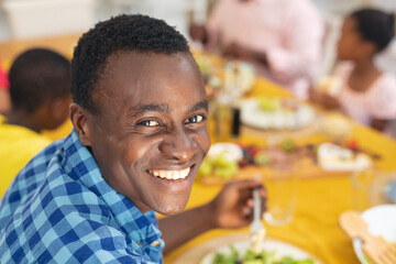 Portrait of smiling african american mid adult man having lunch with family on thanksgiving day - Powered by Adobe