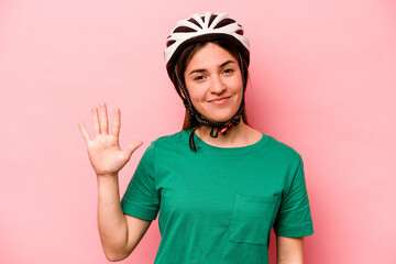 Young caucasian woman wearing helmet isolated on pink background smiling cheerful showing number five with fingers.