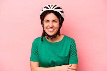 Young caucasian woman wearing helmet isolated on pink background laughing and having fun.