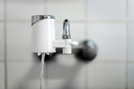 Filtro de agua acoplado en un grifo de cocina. Filtro que permite purificar el agua para poder beber el agua que sale directamente del grifo. 