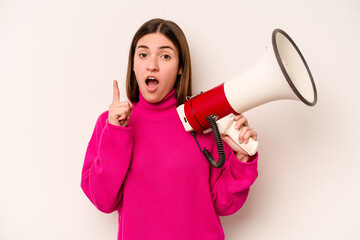 Young caucasian woman holding a megaphone isolated on white background having an idea, inspiration concept.