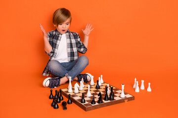 Full length photo of young excited boy sit floor play game unexpected winner success isolated over orange color background