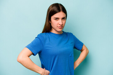 Young caucasian woman isolated on blue background frowning face in displeasure, keeps arms folded.