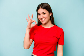 Young caucasian woman isolated on blue background cheerful and confident showing ok gesture.