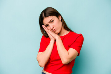 Young caucasian woman isolated on blue background yawning showing a tired gesture covering mouth...