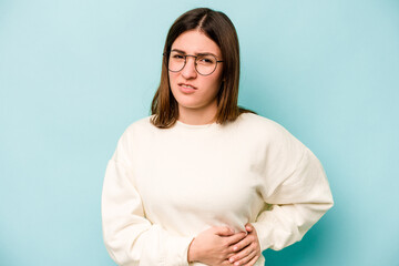 Young caucasian woman isolated on blue background having a liver pain, stomach ache.