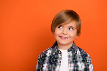 Photo of young cheerful boy curious interested look empty space plan think isolated over orange color background