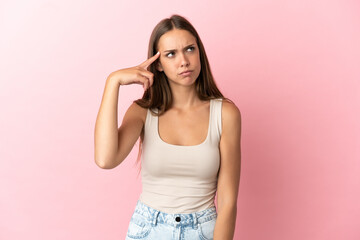 Young woman over isolated pink background making the gesture of madness putting finger on the head