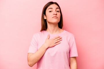 Fototapeta premium Young caucasian woman isolated on pink background taking an oath, putting hand on chest.
