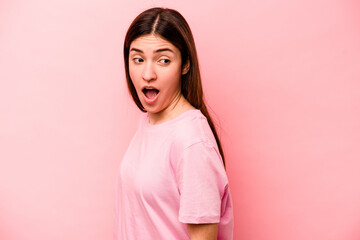 Young caucasian woman isolated on pink background looks aside smiling, cheerful and pleasant.