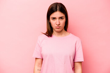 Young caucasian woman isolated on pink background sad, serious face, feeling miserable and displeased.