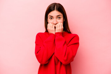 Young caucasian woman isolated on pink background biting fingernails, nervous and very anxious.