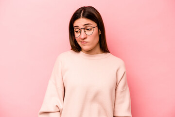 Young caucasian woman isolated on pink background shrugs shoulders and open eyes confused.