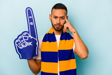 Young sports hispanic fan man isolated on blue background pointing temple with finger, thinking, focused on a task.
