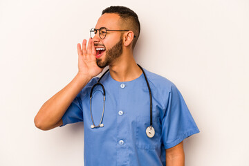 Young hispanic nurse man isolated on white background shouting and holding palm near opened mouth.