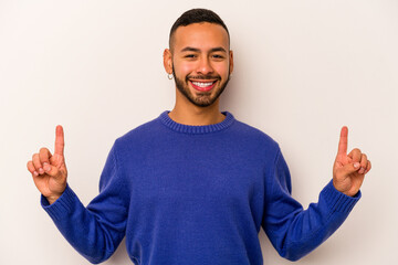Young hispanic man isolated on white background indicates with both fore fingers up showing a blank...