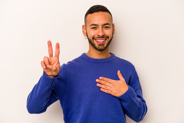 Young hispanic man isolated on white background taking an oath, putting hand on chest.