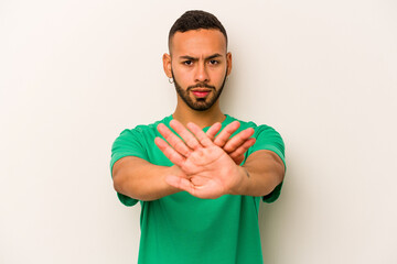 Young hispanic man isolated on white background standing with outstretched hand showing stop sign,...