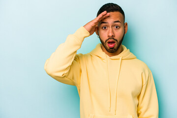 Young hispanic man isolated on blue background shouts loud, keeps eyes opened and hands tense.