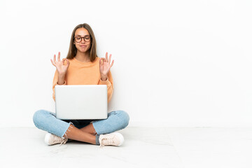 Young woman with a laptop sitting on the floor in zen pose