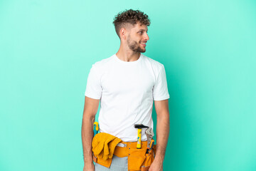 Young electrician blonde man isolated on green background looking side