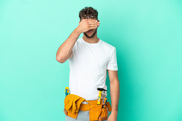 Young electrician blonde man isolated on green background covering eyes by hands. Do not want to see something