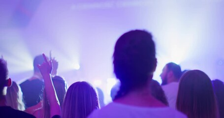 Unrecognizable People with Raised Arms Enjoy Music Live Concert or Show Event with Lights. Christians Worship and Praise on Youth Festival or Conference. 4K back view handheld shot in slow motion